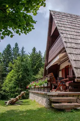 a log cabin with a deck and chairs on it at Wooden Cottage in Jesenice