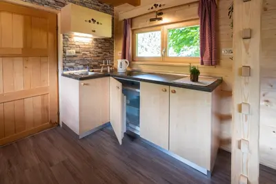 a kitchen with wooden cabinets and a window at Camping Danica Cottage Stan in Bohinj