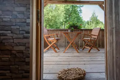 an open door to a deck with chairs and a table at Camping Danica Cottage Stan in Bohinj