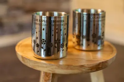 two metal cups sitting on top of a wooden table at Camping Danica Cottage Stan in Bohinj