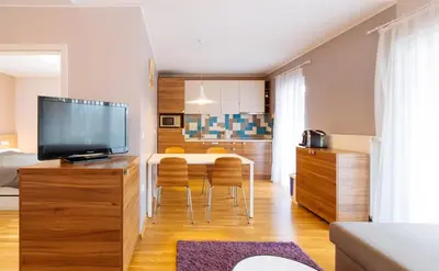 a living room with a table with chairs and a television at Maline Apartments in Bled