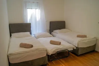 two twin beds in a room with wood floors at Maline Apartments in Bled