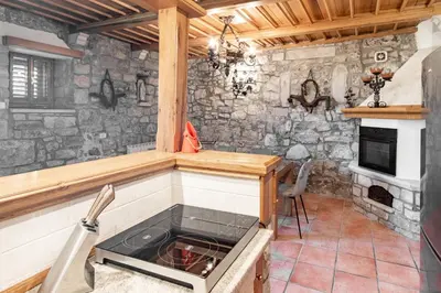 a kitchen with a stone wall with a stove at Apartment Trieste HerMes arT in Sežana