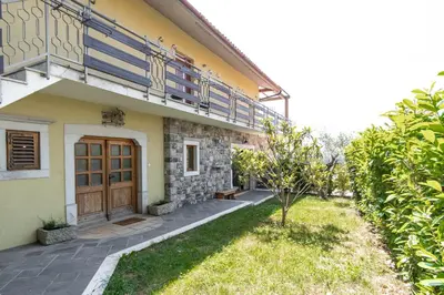 a house with a wooden door and a balcony at Apartment Trieste HerMes arT in Sežana