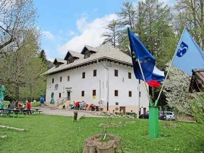 two flags in front of a white building at Dom Pristava in Jesenice