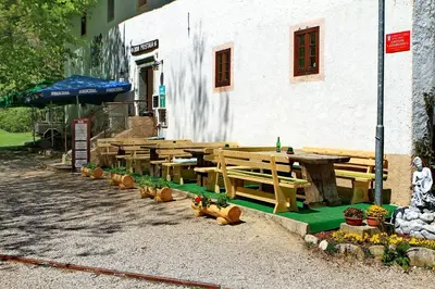 a group of wooden picnic tables in front of a building at Dom Pristava in Jesenice