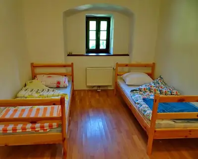two beds in a small room with a window at Dom Pristava in Jesenice