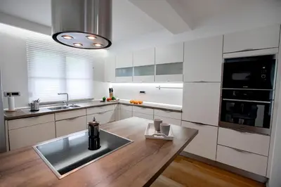 a kitchen with white cabinets and a wooden table at House of Adventure - The Base to explore Slovenia in Laze v Tuhinju