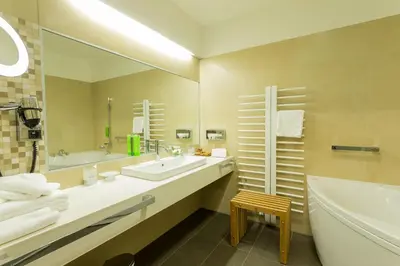 a bathroom with a sink and a tub and a mirror at Hotel Jozef in Idrija