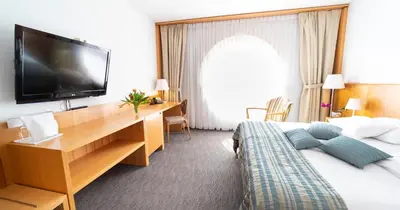 a hotel room with a bed and a desk with a television at Hotel Jozef in Idrija