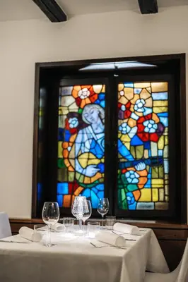 a table with wine glasses in front of a stained glass window at Vila Podvin in Radovljica
