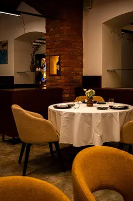 a table in a restaurant with a white tablecloth and chairs at Vila Podvin in Radovljica