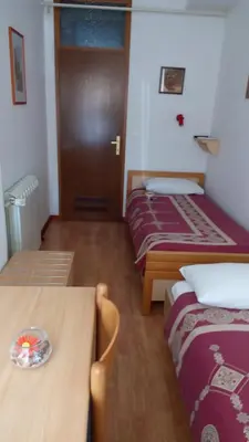 a room with two beds and a table and a door at Accomodation Pertout in Nova Gorica