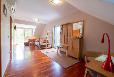 a living room with wood floors and a room with a mirror at Apartments Apple Garden **** in Bled