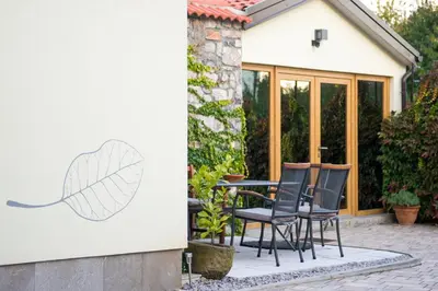 a patio with chairs and a leaf painted on a wall at Zenja Apartments - Free Private Parking - Škocjan caves - Cozy garden in Divača