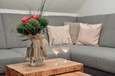 a vase of flowers and two glasses of wine on a table at Apartments Grad Kamen in Begunje na Gorenjskem