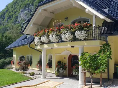 a yellow house with flower boxes on the balcony at Apartments Grad Kamen in Begunje na Gorenjskem