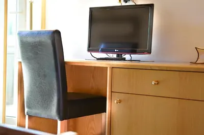 a television sitting on top of a desk with a chair at Penzion Rožič in Bohinj