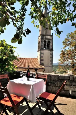 a table with two chairs and a clock tower at Blackbird House Štanjel Historic Center in Štanjel