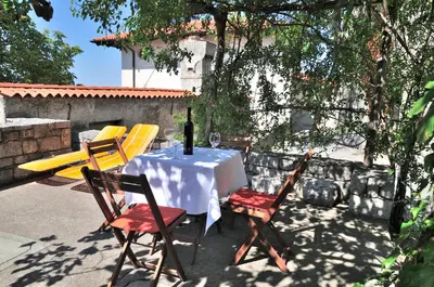 a table with yellow chairs and a bottle of wine at Blackbird House Štanjel Historic Center in Štanjel