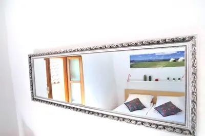 a mirror hanging on a wall with a bed and pillows at Blackbird House Štanjel Historic Center in Štanjel