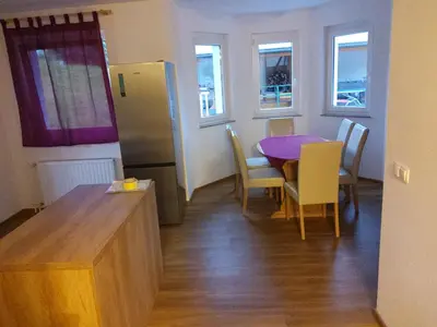 a kitchen and dining room with a table and a refrigerator at Apartma Dominik in Zgornje Gorje