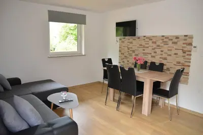 a living room with a wooden table and black chairs at Apartmaji Gaby in Gozd Martuljek
