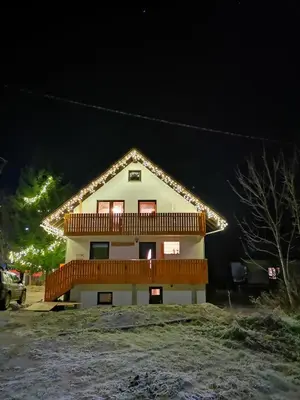 a house with christmas lights on it at night at Apartmaji Gaby in Gozd Martuljek