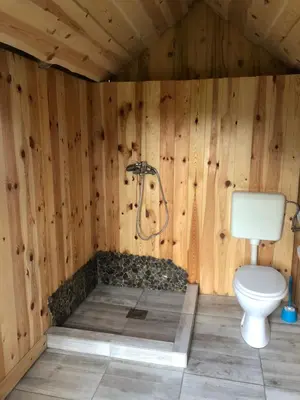 a wooden bathroom with a toilet and a shower at Mountain Lodge Suška Koča in Stahovica