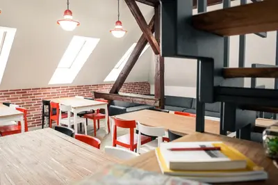 a dining room with tables and chairs and windows at Hostel Vila Pohorje in Slovenj Gradec