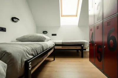 a bedroom with a bed and a bench and a window at Hostel Vila Pohorje in Slovenj Gradec