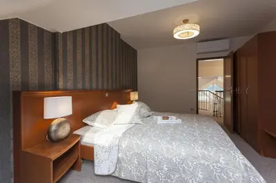 a bedroom with a large bed with a wooden headboard at Duplex Penthouse Aparthotel Rosa in Podčetrtek