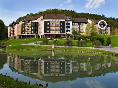 a building with a reflection in a body of water at Duplex Penthouse Aparthotel Rosa in Podčetrtek