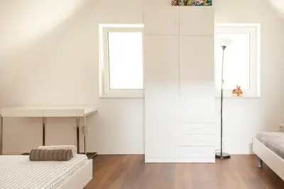 a white bedroom with a bed and a window at Hillhouse Novo mesto in Novo Mesto