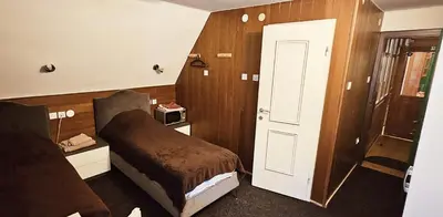 a small room with a bed and a door at Planinski Dom na Travni Gori in Sodražica