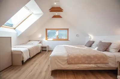 two beds in a attic bedroom with two windows at Apartments Izvir in Bohinj