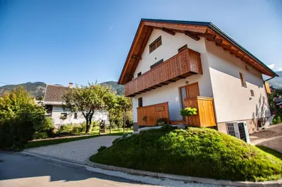 a white house with wooden doors and a driveway at Apartments Izvir in Bohinj