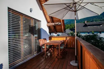 a wooden table and chairs on a balcony with an umbrella at Apartments Izvir in Bohinj