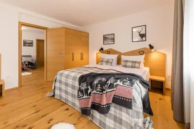 a bedroom with a large bed with a wooden headboard at Apartments and Rooms Kaja in Kranjska Gora