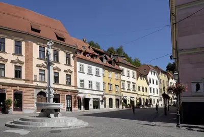 a city street with buildings and a fountain in the middle at City Pearl Apartment in Ljubljana