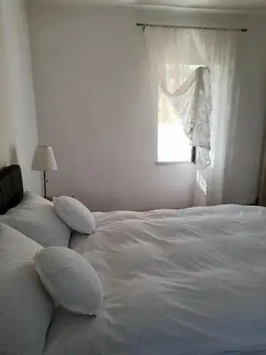 a white bed with pillows in a bedroom with a window at Charming house 