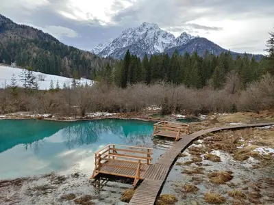 two benches sitting on a walkway near a pool of water at Ajda apartment in Kranjska Gora