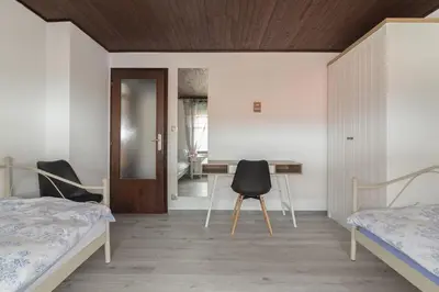 a bedroom with two beds and a desk and a table at Family Apartment NAKITEYA in Ljubljana