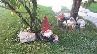 a gnome sitting on a chair under a tree at Family Apartment NAKITEYA in Ljubljana