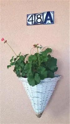 a plant in a white basket hanging on a wall at Family Apartment NAKITEYA in Ljubljana