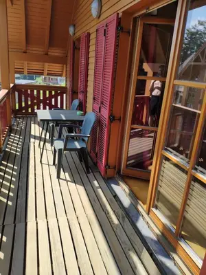a wooden deck with a table and chairs on a house at Antela appartments for up to 5 person on Mariborsko Pohorje in Pohorje