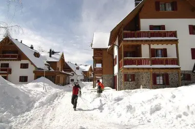 two people standing in the snow in front of a lodge at Antela appartments for up to 5 person on Mariborsko Pohorje in Pohorje