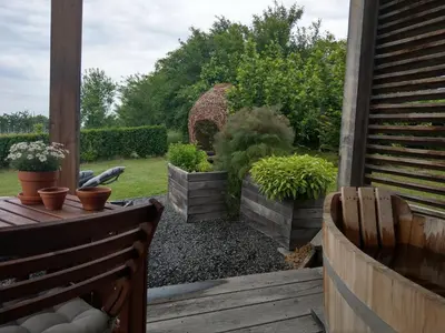 a patio with a wooden table and chairs and plants at Hišice Čarna - Houses Čarna in Puconci