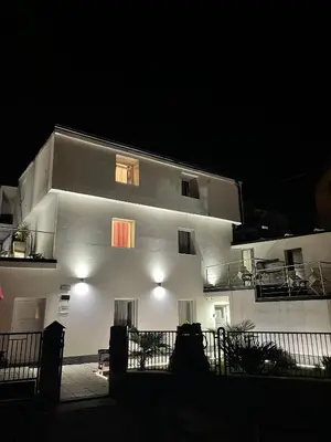 a white building with windows and a balcony at night at Panda Rooms in Maribor