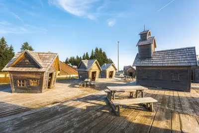 a group of wooden buildings with a picnic table at POHORJE HOUSE Rogla 2 in Oplotnica